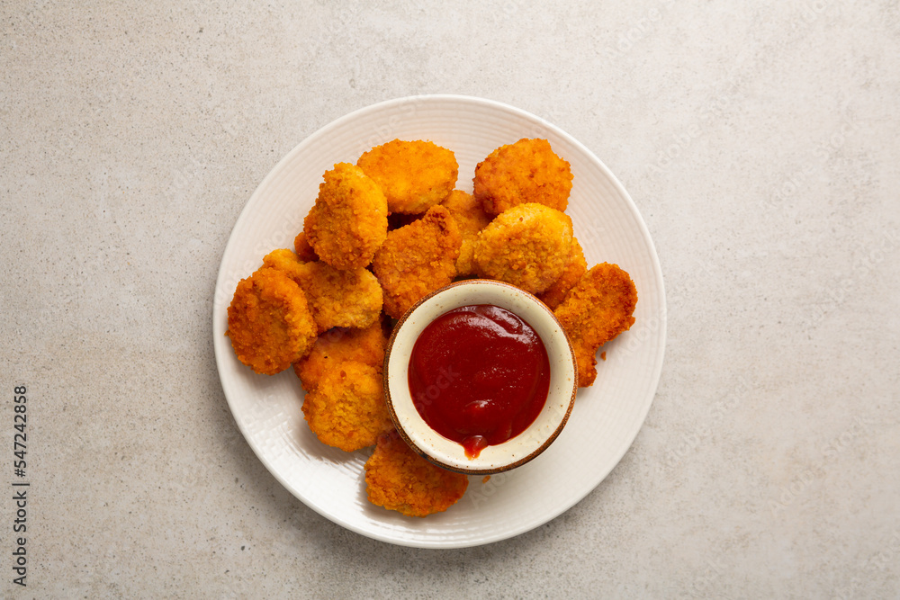 Overhead view of chicken nuggets and dip on light surface Overhead view of chicken nuggets and dip on light surface