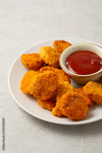 Close up of chicken nuggets and dip on light surface