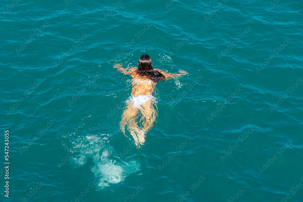 Floating girl in white swimsuits in the blue sea