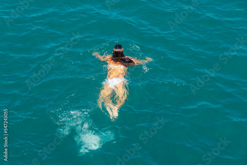 Floating girl in white swimsuits in the blue sea