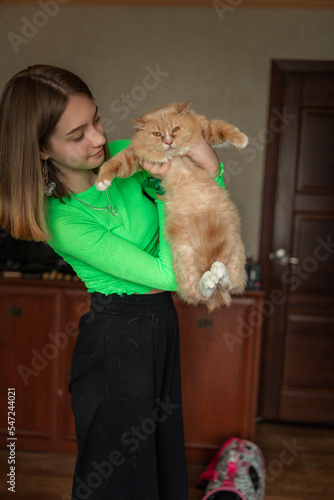 Portrait of a young beautiful blonde girl with a cat in her arms in a home studio.