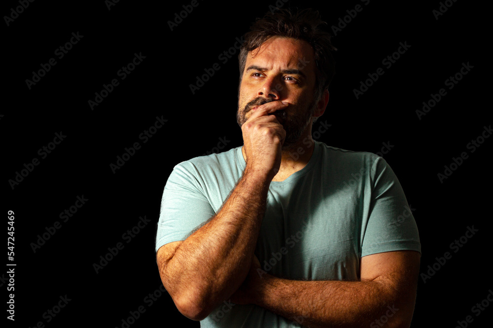 A man with messy hair with a hand on his mouth and looking to nowhere, just thinking. A man with messy hair with a hand on his mouth and looking to nowhere, just thinking.