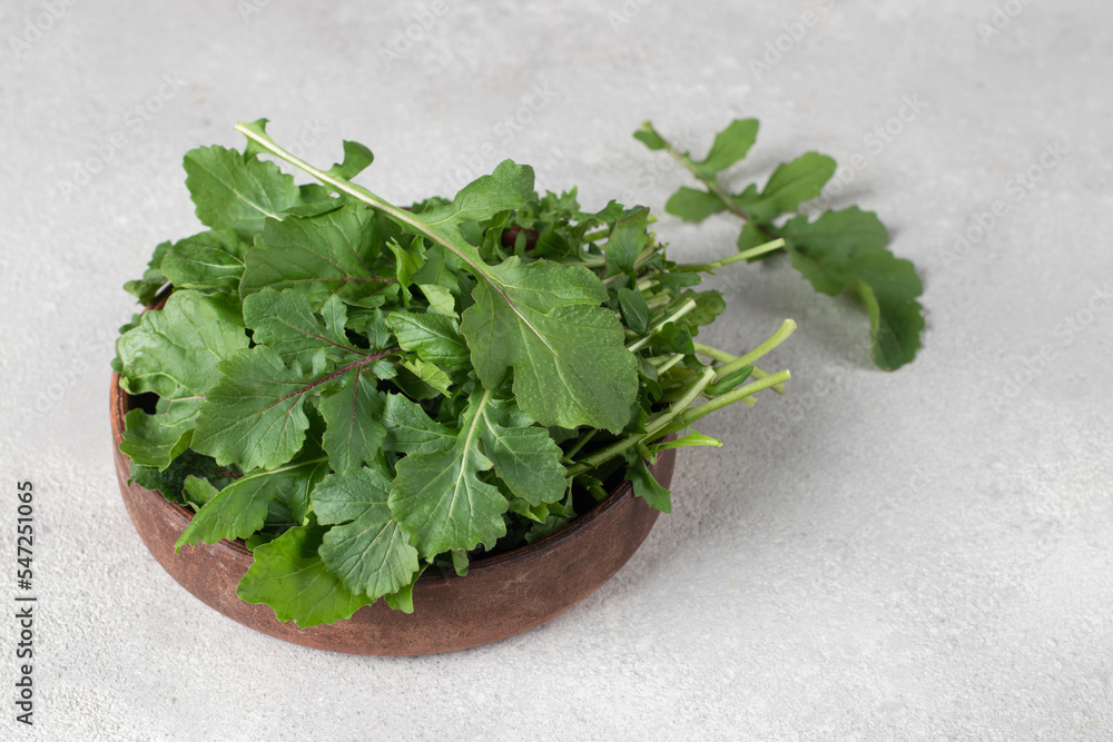 Fresh arugula(rucola, rocket) in brown plate on a light gray background, Copy space Fresh arugula(rucola, rocket) in brown plate on a light gray background, Copy space