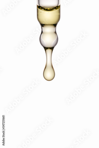 Cosmetic oil dropping out of pipette on white background. Treatment, health, skin care. Macro shot