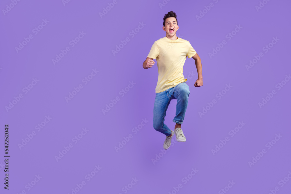 Joyous brunette man running in air hurrying for discounts studio shot isolated on bright background