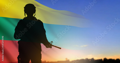 Silhouette of soldier with the flag of Lithuania on background of sunset. Armed forces of Lithuania. Greeting card - Armed Forces day