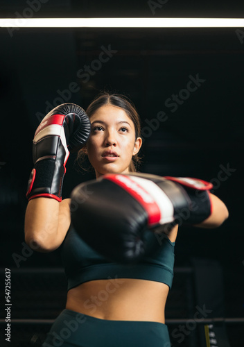 A young Asian girl posing with boxing gloves in a guard position, concept of youth boxing, view from below.