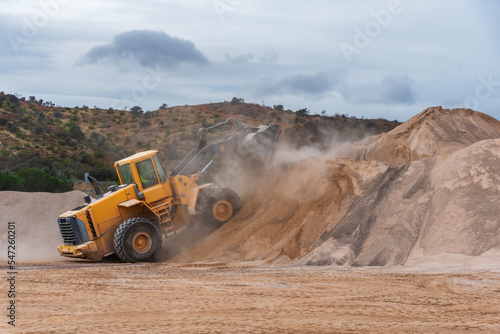 Bulldozer shovel climbing a mountain of sand in a quarry.