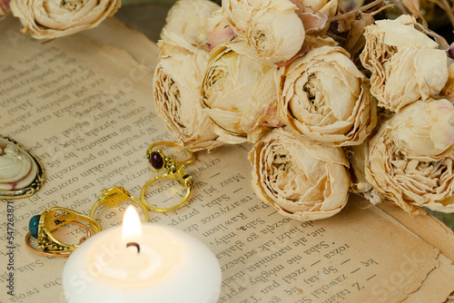 pierścionki, świeczka oraz róże ułożone na starej książce © Andrzej Michaluk