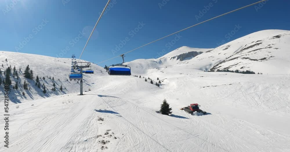 POV from chair ski lift with skiers over blue sky in sunny day with skier ski down the track POV from chair ski lift with skiers over blue sky in sunny day with skier ski down the track