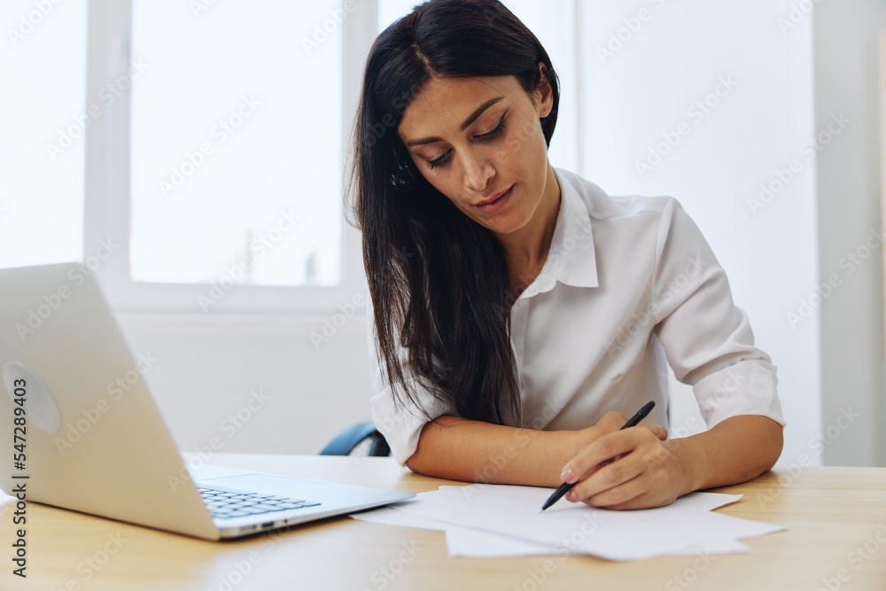 A woman works and learns by writing down text on paper with a pen and checking for errors, studying and teaching in college, business work A woman works and learns by writing down text on paper with a pen and checking for errors, studying and teaching in college, business work