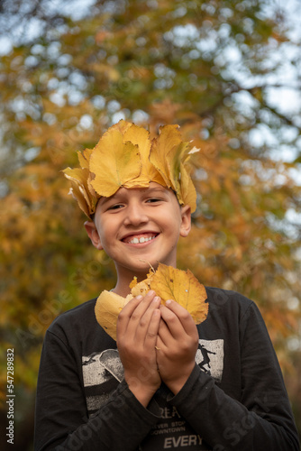 Smiling boy with crown of leaves celebrates autumn season