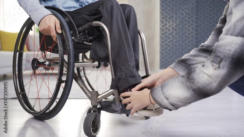 Girlfriend helping her paraplegic boyfriend. Care and disability concept.
Woman helps paralyzed legs of a disabled person sitting in a wheelchair.
