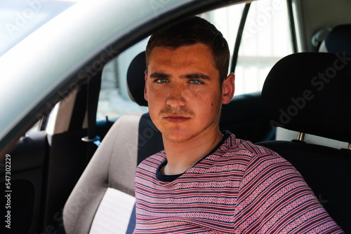 Defocus happy smiling caucasian young man sitting in car. 20s guy looking from open window. Silver grey gray car. Attractive brunette men in vehicle. Buyer or dealer concept. Out of focus