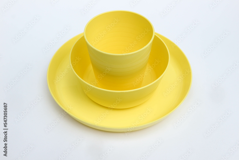 Yellow plastic dinnerware, bowl, plate and cup isolated on white background Yellow plastic dinnerware, bowl, plate and cup isolated on white background