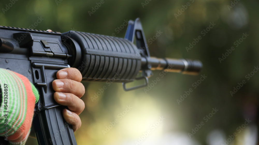 Air soft gun holding by hand aiming in a shooting range, soft and selective focus on the gun Air soft gun holding by hand aiming in a shooting range, soft and selective focus on the gun
