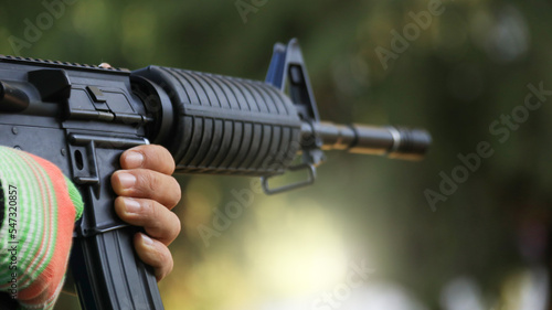 Air soft gun holding by hand aiming in a shooting range, soft and selective focus on the gun 