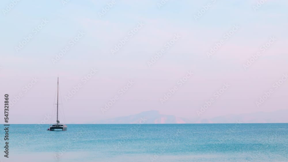 Yacht - Catamaran in the ocean against the backdrop of mountains and a pink sky on a sunny summer day. Yacht - Catamaran in the ocean against the backdrop of mountains and a pink sky on a sunny summer day.