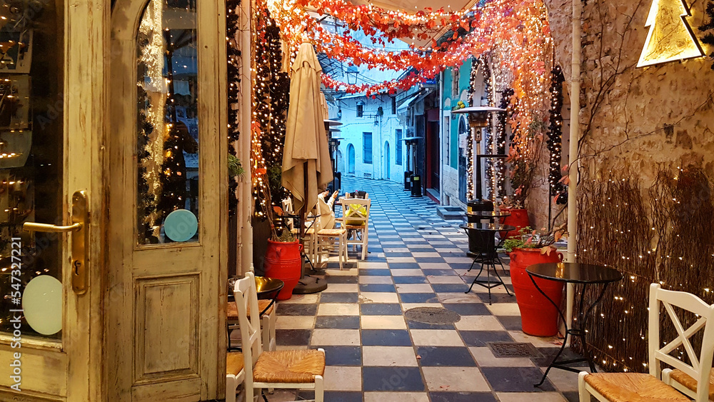Fototapeta premium xmas season street cafe in ioannina city greece lights tables chairs pedestrian street like chessboard