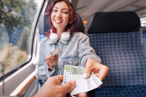 A girl on a public transport train passes euro banknotes to a stranger. The concept of credulity to fraud or scams photo