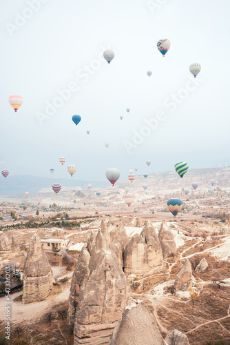 Obraz na płótnie Stunning view some hot air balloons flying over the beautiful Cappadocia landscape during a cloudy day. Goreme, central Antolia, Turkey. w salonie