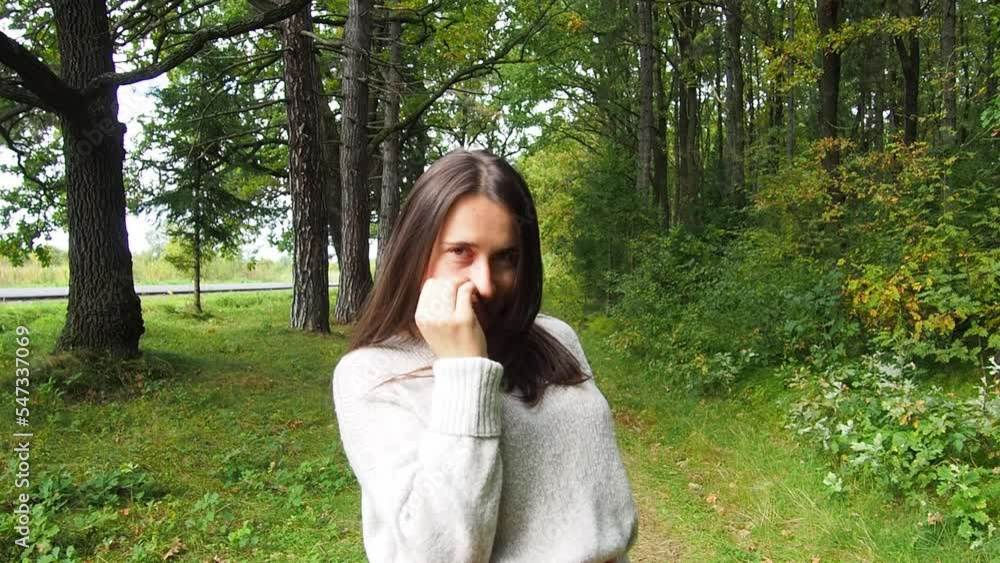 Young girl corrects long dark hair. Beautiful woman in gray sweater and red skirt posing in the forest on a sunny autumn day. Walking and relaxing in the woods.