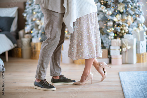 Romantic couple standing near Christmas tree at home and hugging