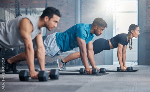 Group, workout and dumbbell push up at gym for muscle, power or strength. Teamwork, sports or energy of people, athletes or bodybuilder friends exercise or training at fitness center for healthcare.