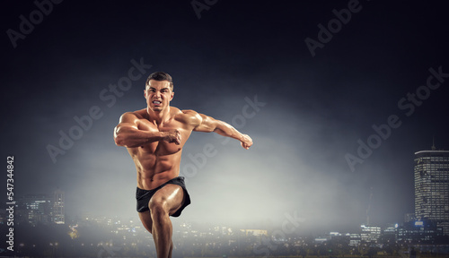 Male runner against dark background © Sergey Nivens