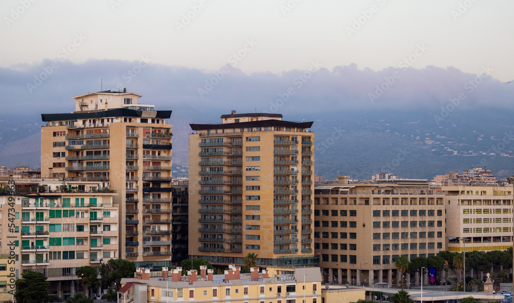 Residential Homes in city with mountains in background in Palermo, Sicily, Italy. Sunrise Sky.
