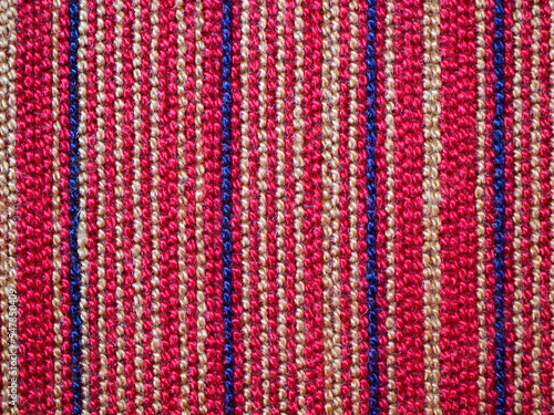 A piece of fabric placemat with colourful (red, navy, beige) pattern line.