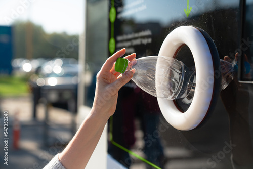 Woman uses a self service machine to receive used plastic bottles and cans on a city street	 photo