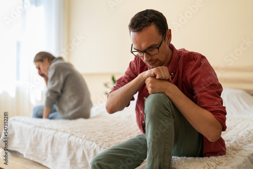 Upset man and woman sad after learning eviction from home after late mortgage payment or lack of money to pay rent. Unhappy Caucasian spouses sit on different sides of bed in apartment bedroom
