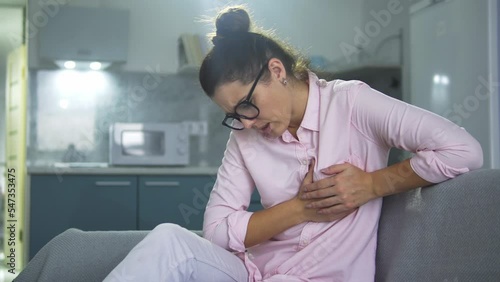 Young woman in pink shirt touching and massaging sore breast, feeling pain, finding some seal, inflammation of the mammary glands, mastitis, breast cancer awareness