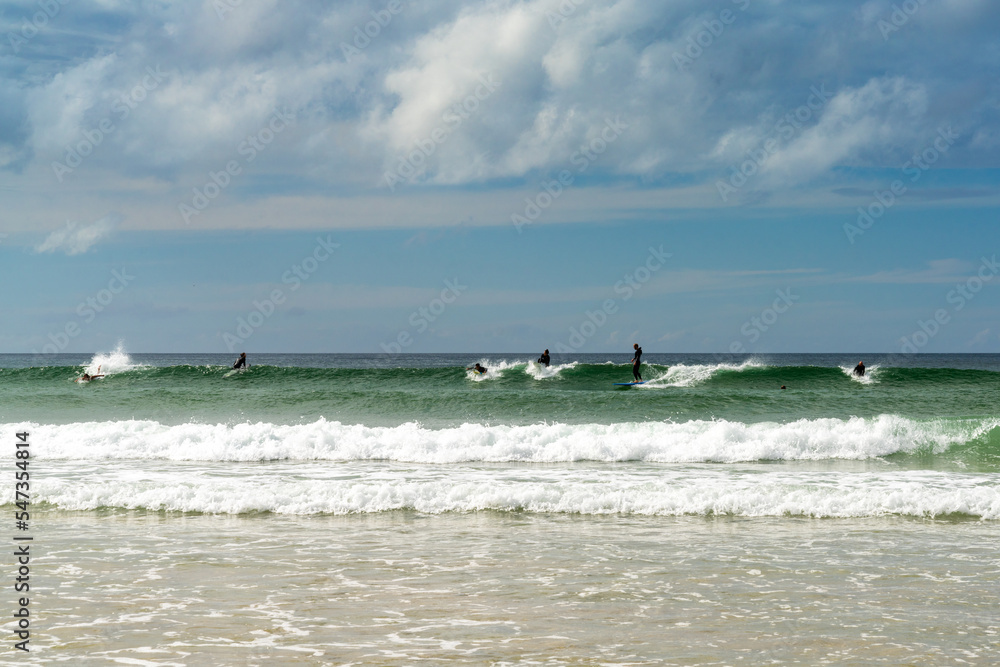 surfers enjoying a summer day in the waves at Fistral Beach