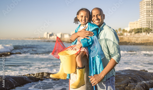 Father, child and family fishing trip at sea learning about nature and having fun on vacation in summer. Portrait of man and girl together teaching kid about fish with beach bucket and net at ocean