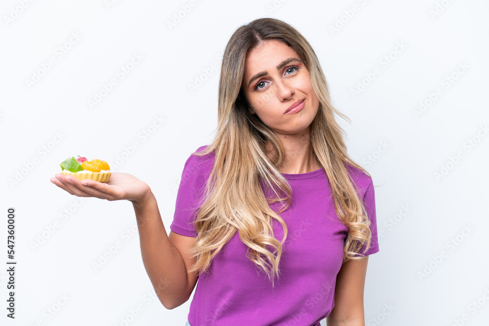 Young pretty Uruguayan woman holding a tartlet isolated on white background with sad expression Young pretty Uruguayan woman holding a tartlet isolated on white background with sad expression