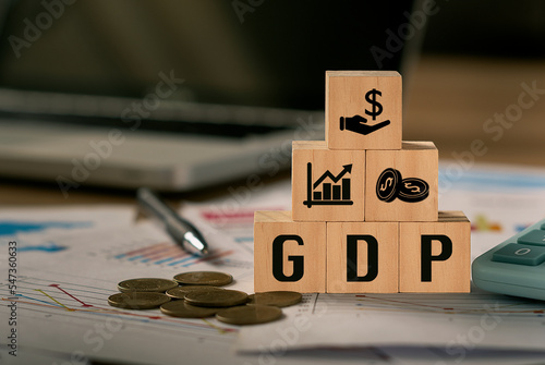 GDP, Gross Domestic Product symbol, word 'GDP' in a wooden block and computer-backed background.  There was a coin placed beside the wooden block.  The concept of gross domestic product, or GDP. photo
