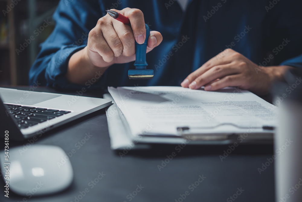 Man stamping approval of work finance banking or investment marketing documents on desk. - obrazy, fototapety, plakaty 