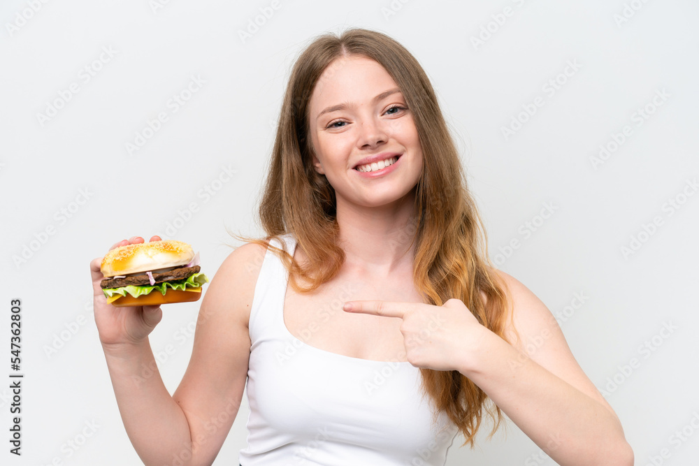 Young pretty woman holding a burger isolated on white background and pointing it Young pretty woman holding a burger isolated on white background and pointing it