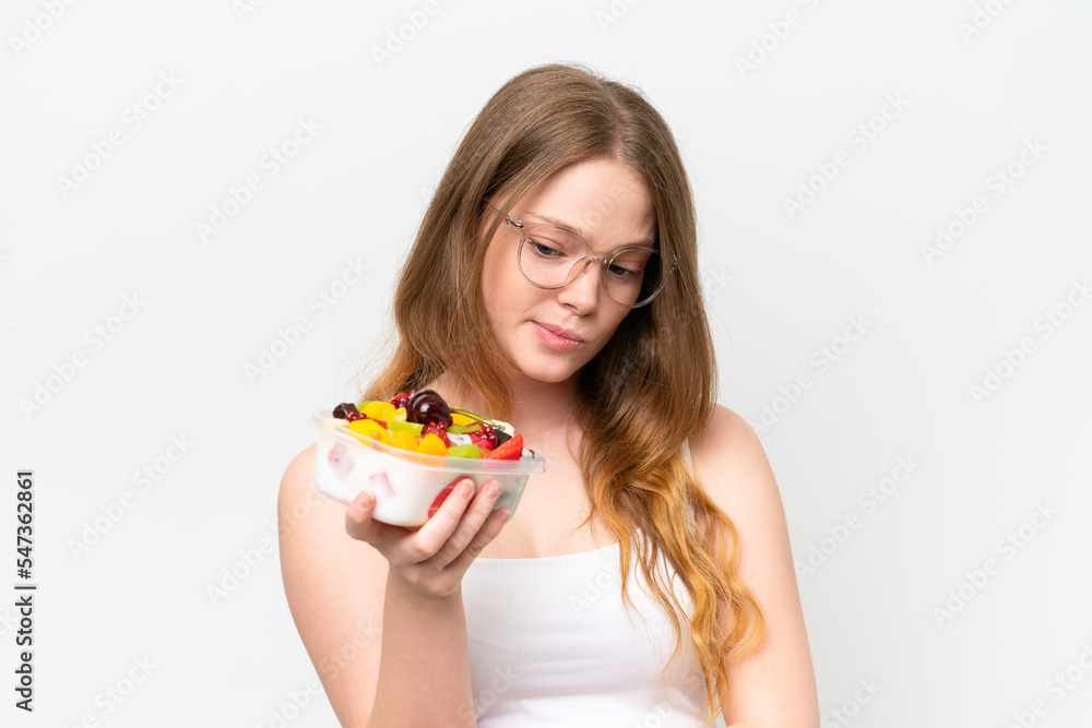 Young pretty woman holding a bowl of fruit isolated on white background with sad expression