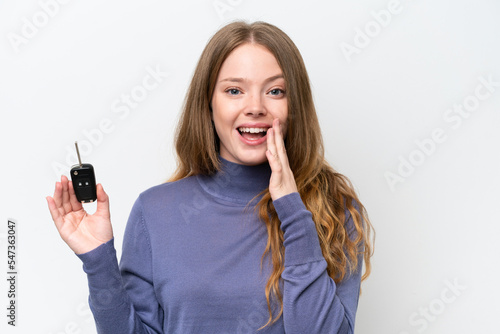 Young caucasian woman holding car keys isolated on white background shouting with mouth wide open