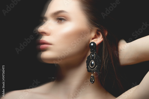 Beauty, fashion, style, jewelry and make-up concept. Beautiful and sexy looking brunette woman with fancy black earrings with gemstones studio portrait. Motion blur effect applied