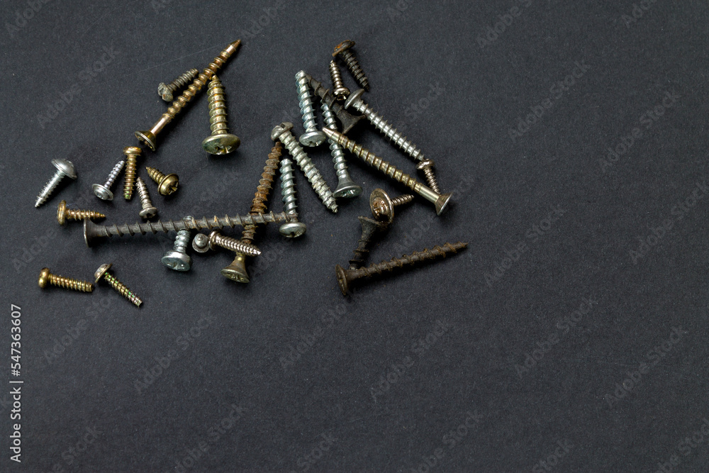 scattering of small screws of different sizes and shapes on a dark background scattering of small screws of different sizes and shapes on a dark background