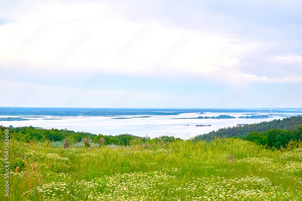 Summer spring evening river Dniper flowing among flowering green hills.