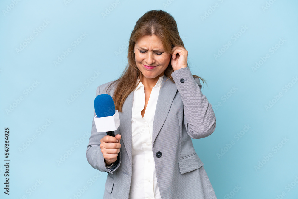 Middle-aged TV presenter woman over isolated blue background frustrated and covering ears Middle-aged TV presenter woman over isolated blue background frustrated and covering ears