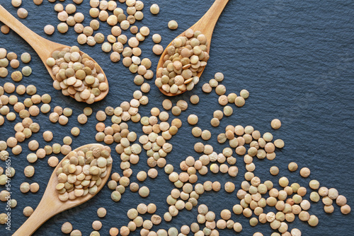 Lentil in three wooden spoons on black background. Flat lay, copy space photo