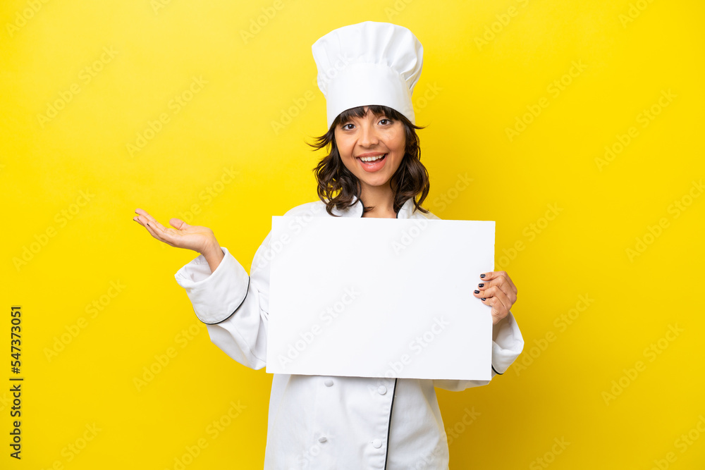 Young chef latin woman isolated on yellow background holding an empty placard with surprised expression Young chef latin woman isolated on yellow background holding an empty placard with surprised expression