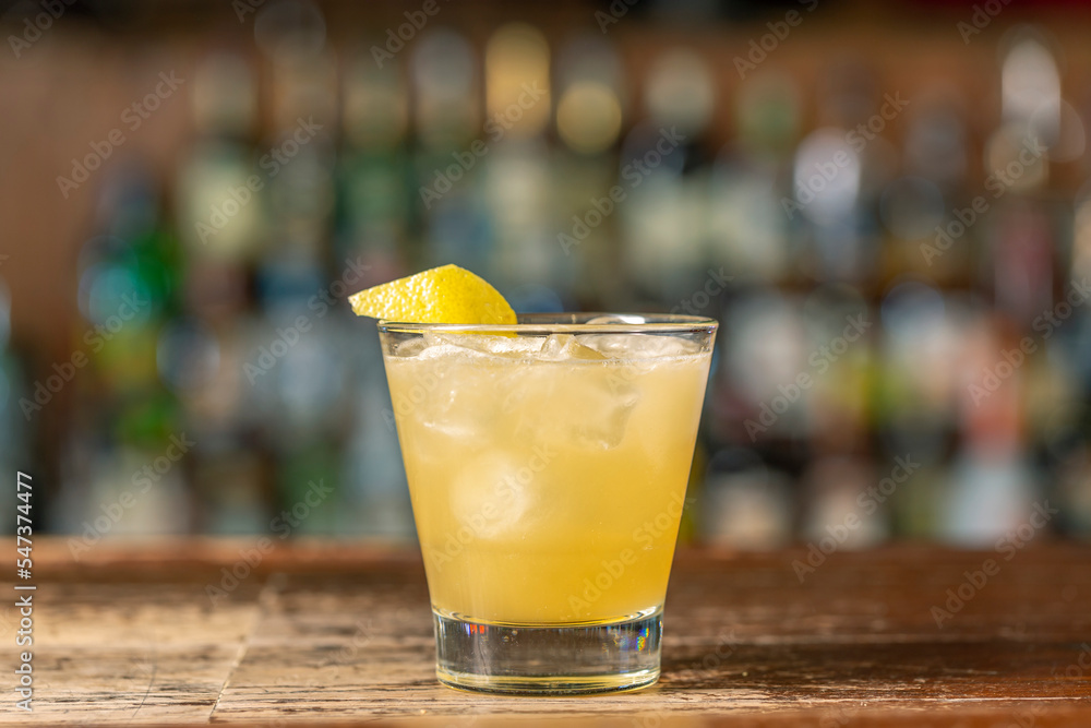 Penicillin cocktail on the bar. Blurred background.Summer refreshing drink, side view Penicillin cocktail on the bar. Blurred background.Summer refreshing drink, side view