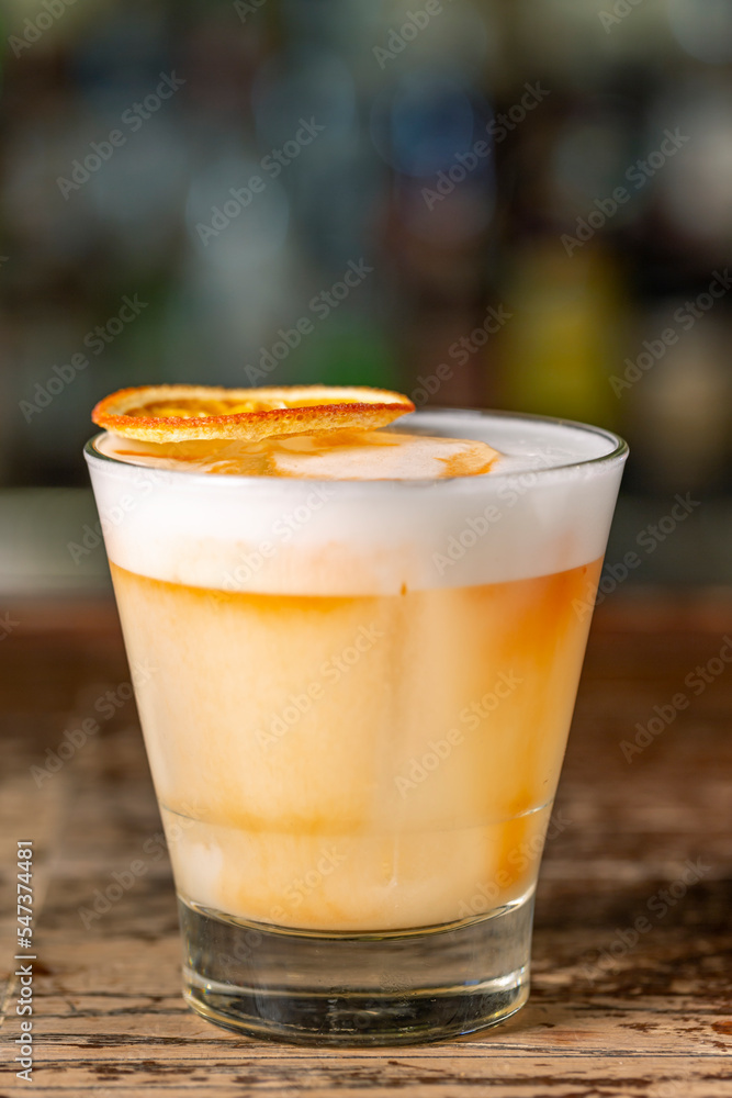 Vanilla Sour cocktail with egg white and lemon juice on the bar. Vanilla Sour cocktail with egg white and lemon juice on the bar.